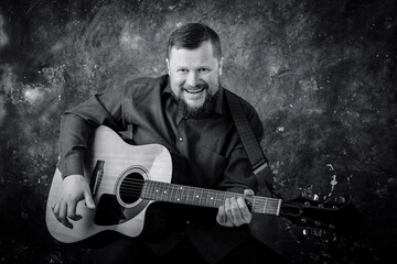 Mature musician plays acoustic guitar emotional studio portrait.