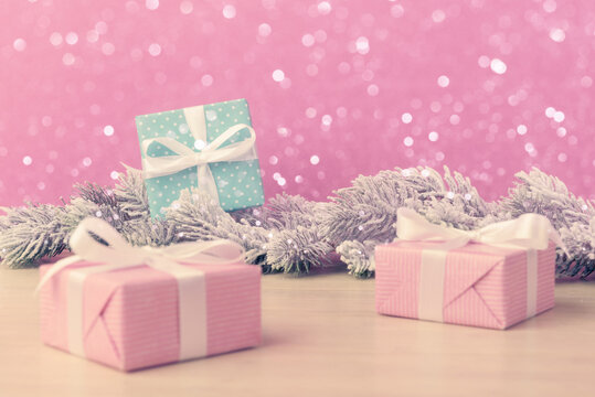 Gift boxes with frosty fir tree branches over pink holiday background