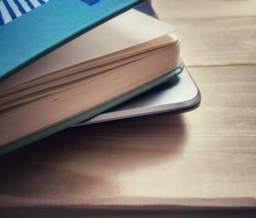 Turquoise closed notebook near laptop on wooden table