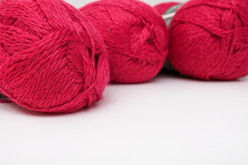 Red pink colorful skeins of yarn close up, fuchsia color woolen yarn for crochet and knitting, hobby and handmade concept, copu space