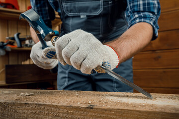 male carpenter hammers wood with a chisel. carpentry tools.