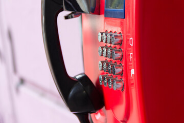 Red street payphone with round stainless steel buttons close-up. An outdated way of communication.