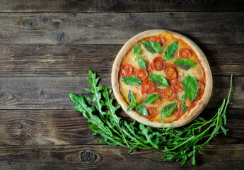Top view to Italian homemade pizza Margarita with tomato, mozzarella and basil on a wooden board