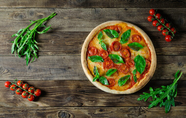 Top view to Italian homemade pizza Margarita with tomato, mozzarella and basil on a wooden board