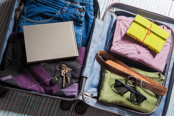 SÃO PAULO, BRAZIL - JAN 10, 2017 : Preparing open travel bag with clothes, accessories, keys, sunglasses, notebook and book, travel and vacation concept, travel concept.