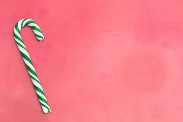 Natural Christmas candy cane (green and white) on pink background. Copy space.