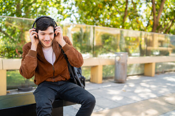 Young man listening music with headphones outdoors.
