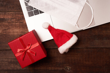 Online shopping for Christmas, a laptop on a table, gift box, xmas cap and mask