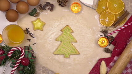 A young woman decorates a festive Christmas cookie in the form of a Christmas tree with colored icing. View from above.