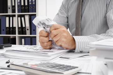 business problem concept - disappointed businessman has trouble and tears up reports