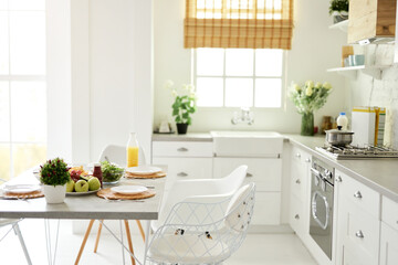 Modern bright white kitchen interior with wooden and white details. Healthy breakfast with fruits and salad on the kitchen table