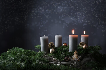 Second advent with two burning candles on fir branches with Christmas decoration against a dark...
