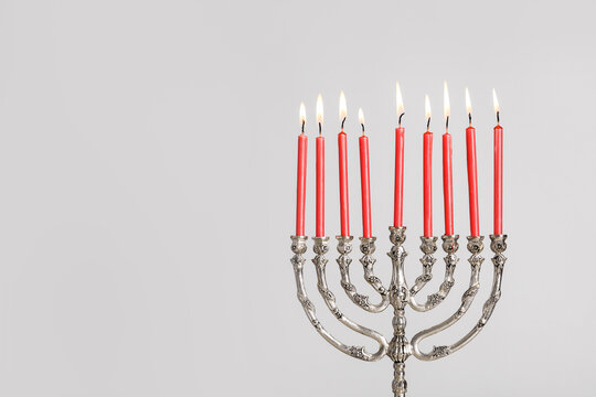 Silver menorah with burning candles on light grey background, space for text. Hanukkah celebration