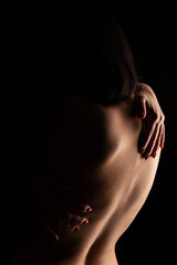 Nude female torso on black background shot from behind. Muscular female back. 