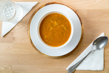 bowl of harira spoon and water on a wooden table