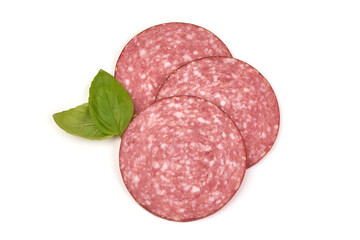 Sliced salami sausage with basil leaves, close-up, isolated on white background