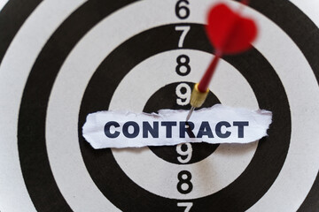 A piece of paper with the text is nailed to the target with a dart - CONTRACT