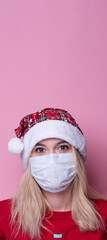 Young woman with medical mask and santa hat on pink  background. Christmas on quarantine. mask safe from coronavirus covid-19 isolated . Happy New Year celebration  merry holiday concept. panorama. 