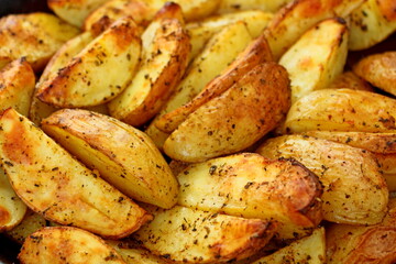 Baked potato wedge with herbs background - homemade organic vegetable. Vegan potato wedge baked snack food meal. Golden rustic country baked potato wedge fries top view - crispy roasted sweet chips