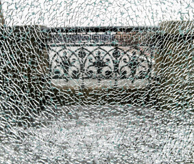 cracks on broken tempered glass exterior, outdoor background. Broken hardened glass on the background of a city street, road. toughened glass in the cracks behind the bridge fence.