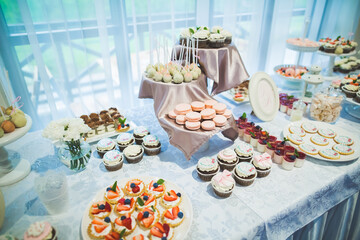 Delicious and tasty dessert table with cupcakes shots at reception closeup