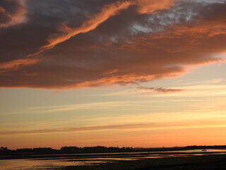 Naklejka na ściany i meble Sunset over the bay and a large artistic cloud