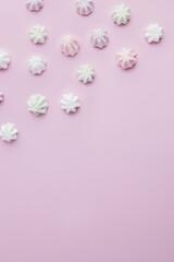 Fototapeta na wymiar Colorful meringues on pastel pink background
