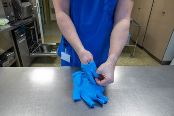 hospital employee takes off his blue protective gloves