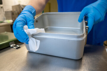 member of an operating department cleans instrument containers with a cleaning cloth
