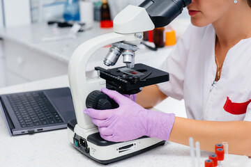 An infectious disease doctor works at a close-up microscope. Study of viruses and bacteria in the medical laboratory