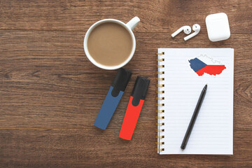 notepad with Czech flag, wireless headphones, coffee cup, pen, markers on brown table, study concept 