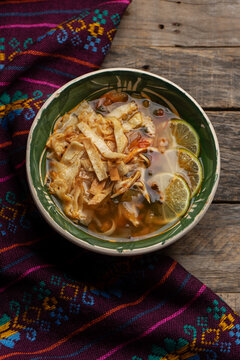 Mexican lime soup with chicken on wooden background