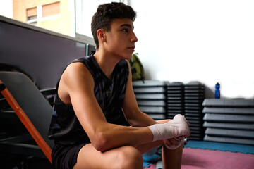Boxer man using bandages before fight in boxing gym