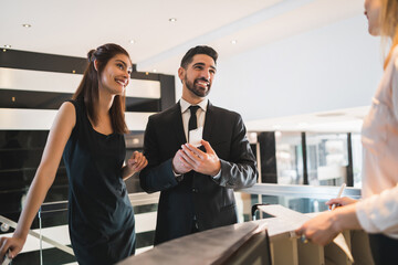 Two business people check-in at hotel reception.