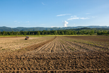 Farming with tractor and plow in field with mountain Papuk in the background, Croatia