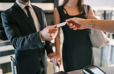 Business people makes card payment at check-in at reception.