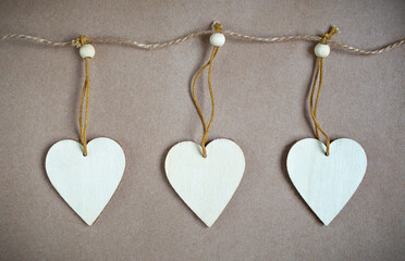 three wooden hearts hang on a thin rope with copy space