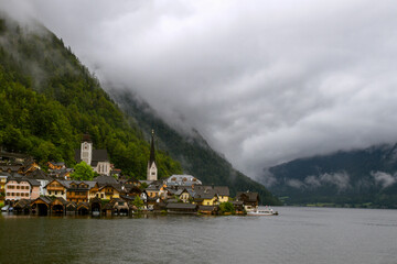 Fototapeta na wymiar Hallstatt, Austria. View to Hallstattersee Lake and Alps mountains summits. Ancient houses at lake banks with chapel. Tourism in Austria. The Alps are a popular tourist destination. Europe.