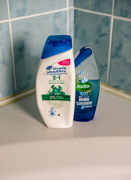 Norwich, Norfolk, UK - November 29 2020. An illustrative editorial photo of a bottle of Head and Shoulders 2 in 1 hair shampoo and conditioner and Radox shower gel on the side of a white bath