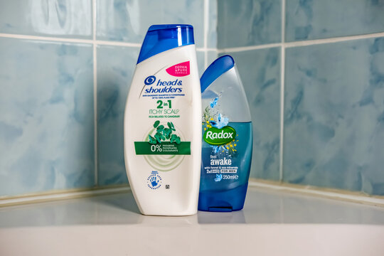 Norwich, Norfolk, UK - November 29 2020. An illustrative editorial photo of a bottle of Head and Shoulders 2 in 1 hair shampoo and conditioner and Radox shower gel on the side of a white bath