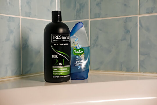 Norwich, Norfolk, UK - November 29 2020. An illustrative editorial photo of a bottle of TRESemme 2 in 1 hair shampoo and conditioner and a bottle of Radox shower gel on the side of a white bath