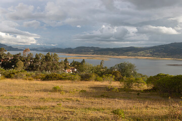 Beautiful shot a nature landscape of colombian lake with andean mountains and white clouds at background in afternoon golden hour