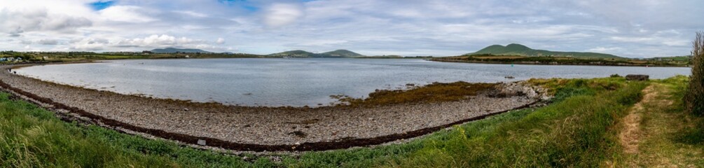 Dramatic morning scene of the coast with typical irish weather.. Mountain and lake in background.