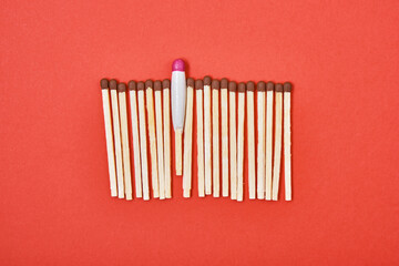 matches are laid out in a row on a red background, one waterproof match among simple matches