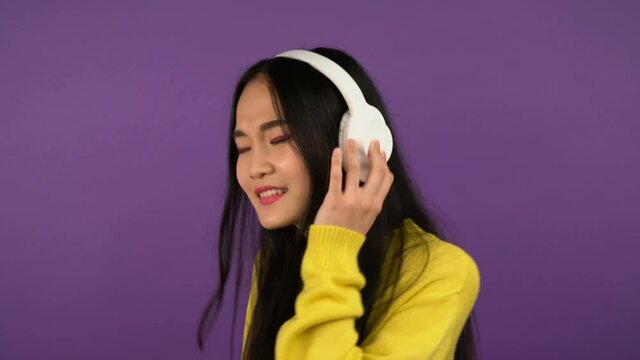 portrait of asian woman listening to music. Isolated on purple background. 4K