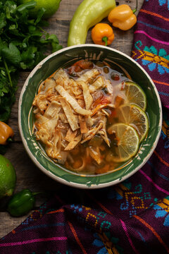 Mexican lime soup with chicken on wooden background