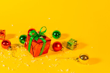 Gift box with a Christmas present on a yellow background, among the New Year's decorations
