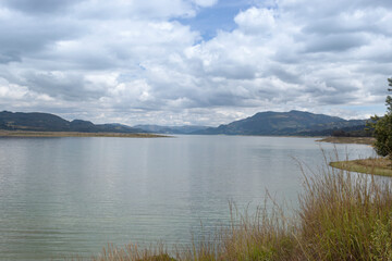 Beautiful summer scene, of a Colombian lake with mountains and blue sky reflected into water. 