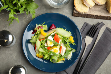 Delicious salad with crab sticks and lettuce on grey table, flat lay