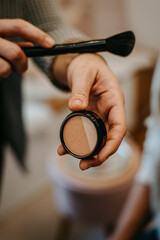 Female makeup artist picks up a blush with eyeshadow, close-up. Professional make-up artist in the process of creativity.